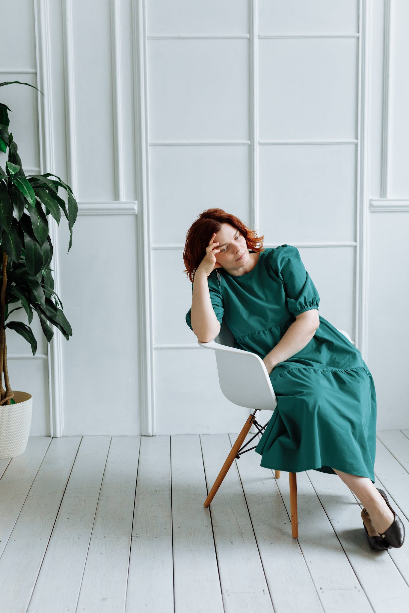 Woman in Green Dress Sitting on a Chair while in Deep Thoughts